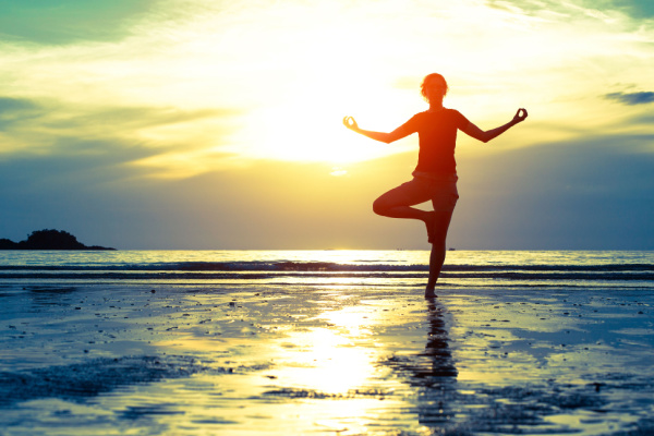 kvinna i yogaposition på strand